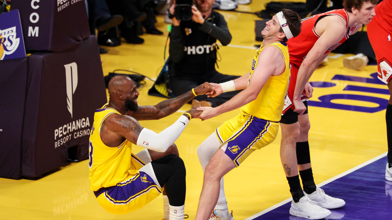Austin Reaves #15 of the Los Angeles Lakers picks up LeBron James #23 of the Los Angeles Lakers after a play during an NBA basketball game against the Chicago Bulls, Thursday March 12, 2026 in Los Angeles, Calif.