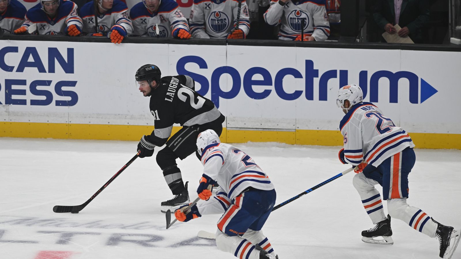 Kings Scott Laughton (21) pushes the puck past two defenders