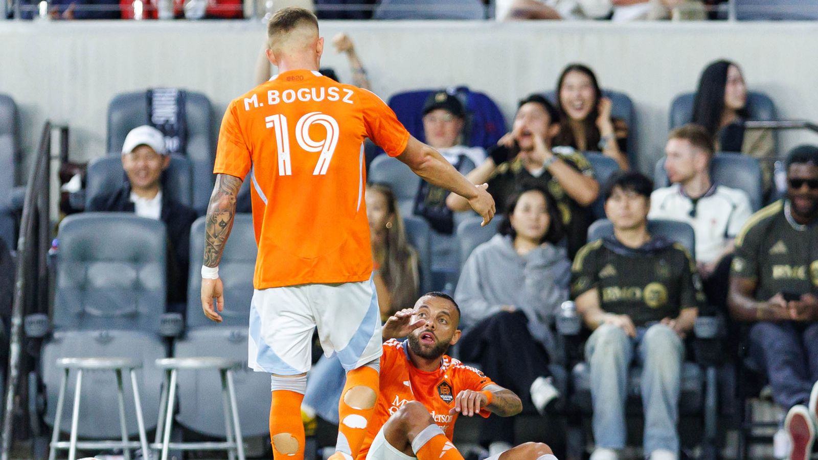 Guilherme Augusto #20 of Houston Dynamo FC helped up by Mateusz Bogusz #19