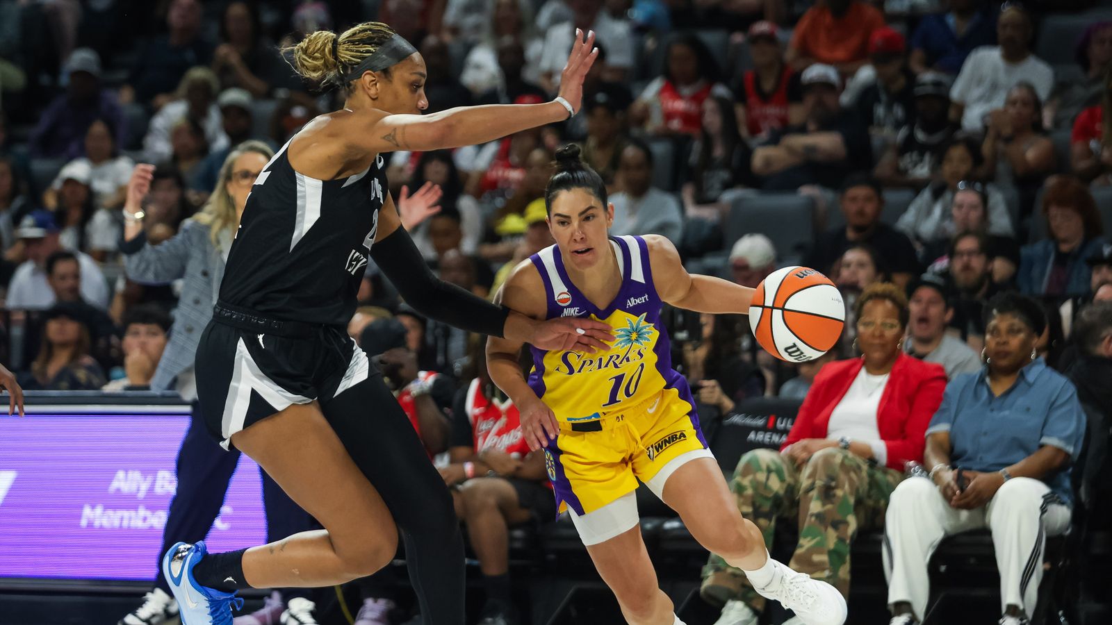 Kelsey Plum drives past A'ja Wilson during a tense WNBA game.