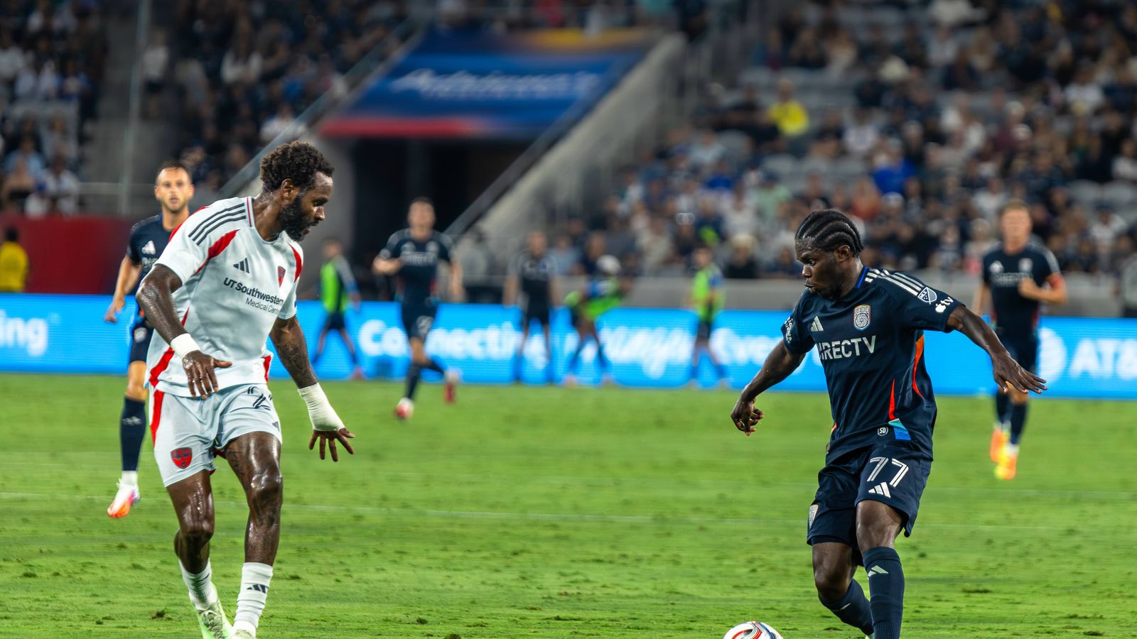 Alex Mighten challenges Sebastien Ibeagha in a key defensive moment.