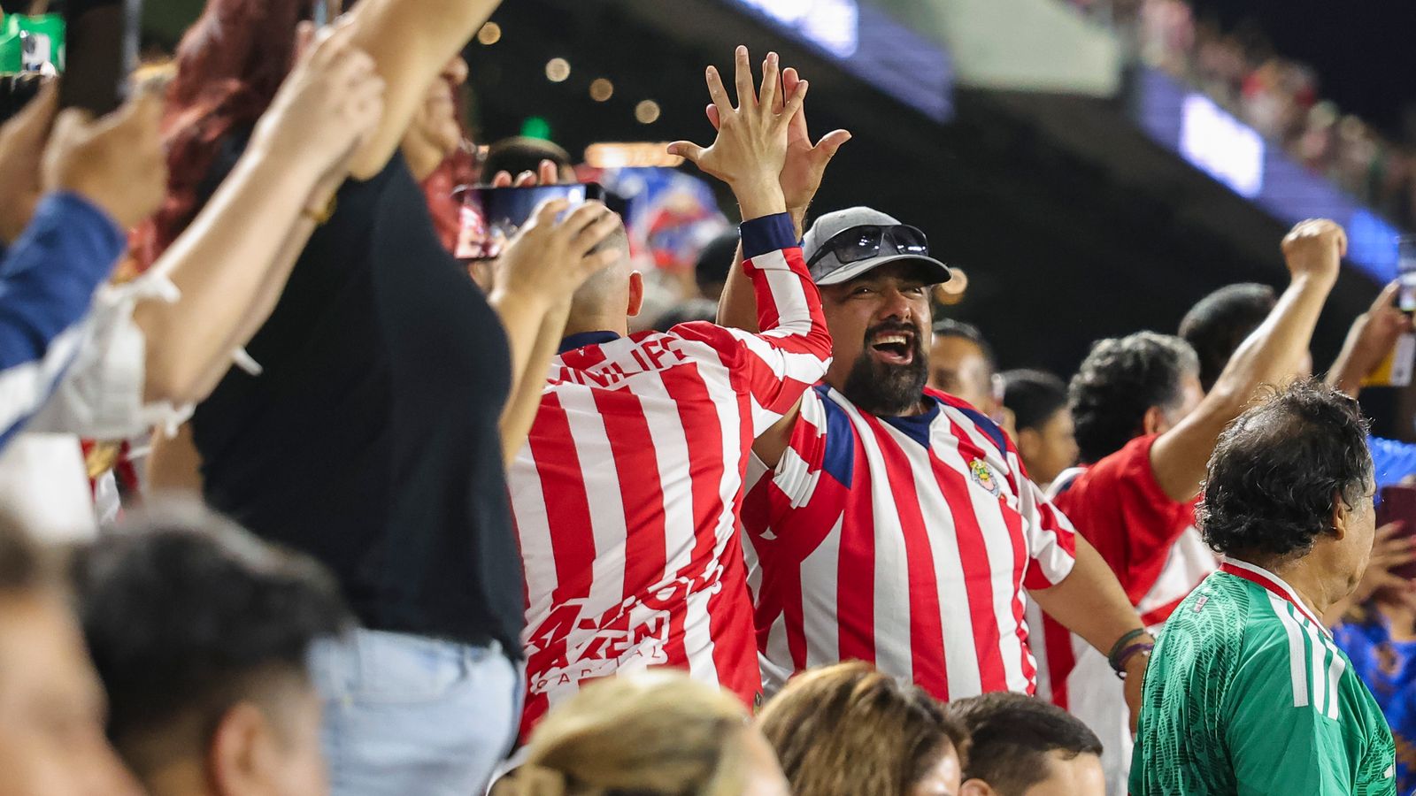Chivas fans celebrate a goal with high fives