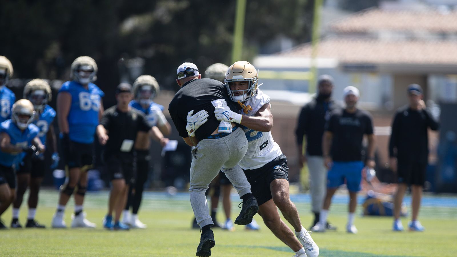 UCLA coaches join player drills at Wasserman Football Center.
