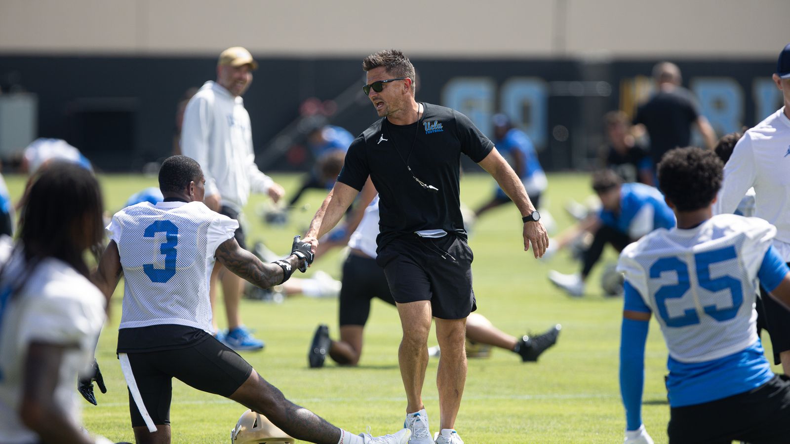 Coach Bob Chesney greets UCLA players during practice.