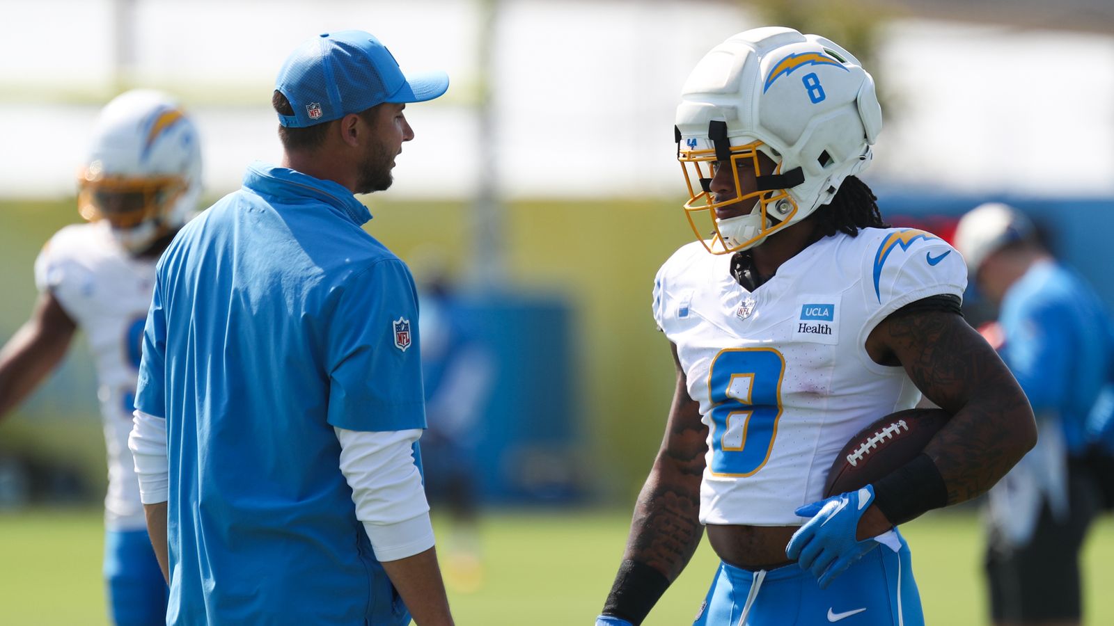 Omarion Hampton #8 discusses strategy with coach Max McCaffrey