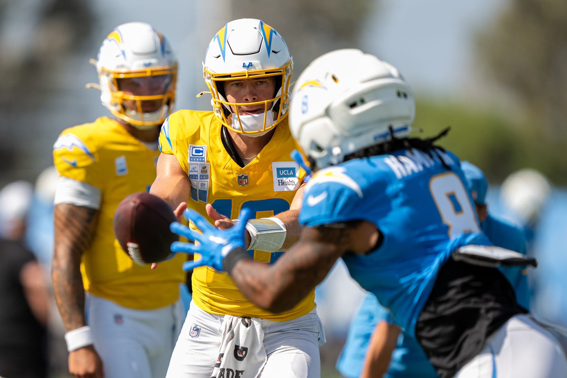 Justin Herbert tosses the ball to Omarion Hampton