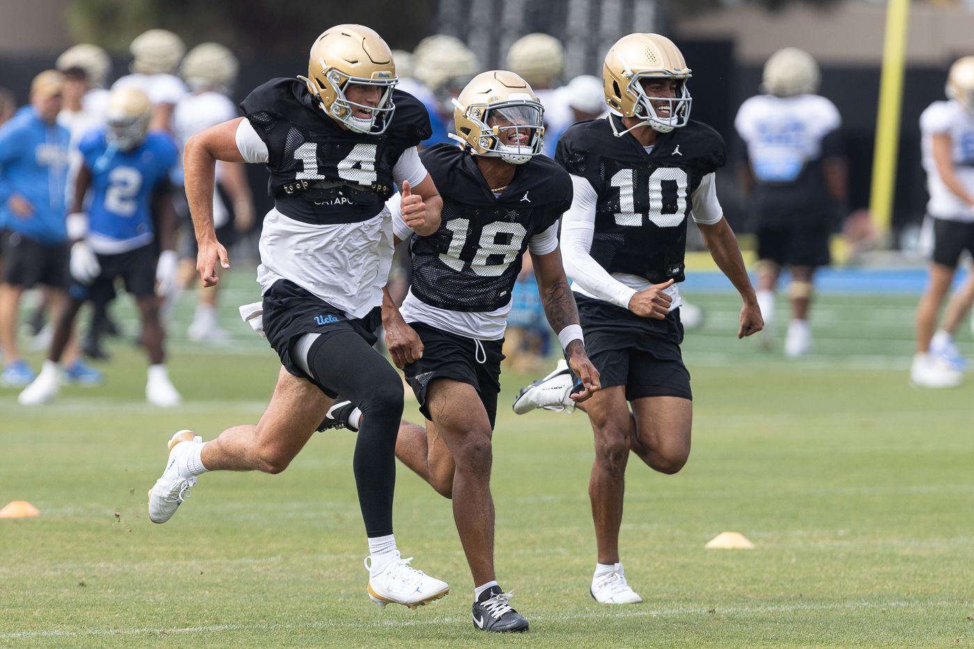 UCLA quarterbacks sprint during a practice session