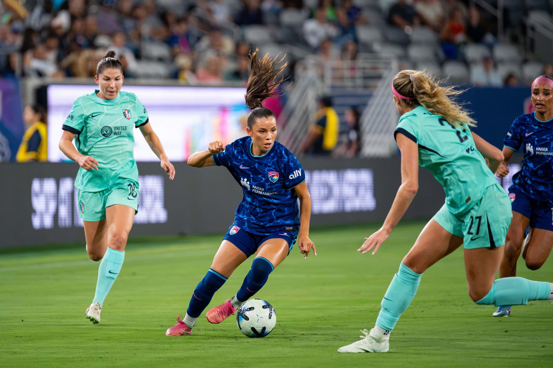 Melanie Barcenas challenges KC Current defenders in a tight contest.