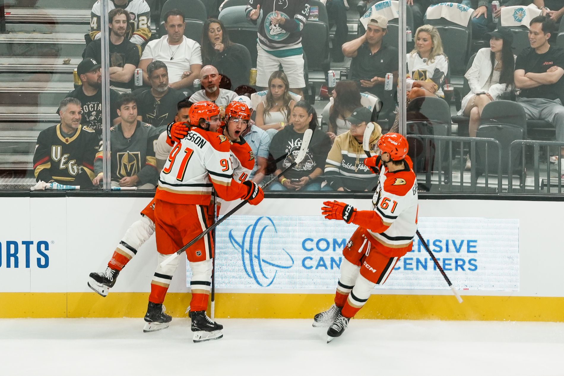 Ducks' Carlsson, Sennecke, and Gauthier celebrate a goal at T-Mobile Arena.