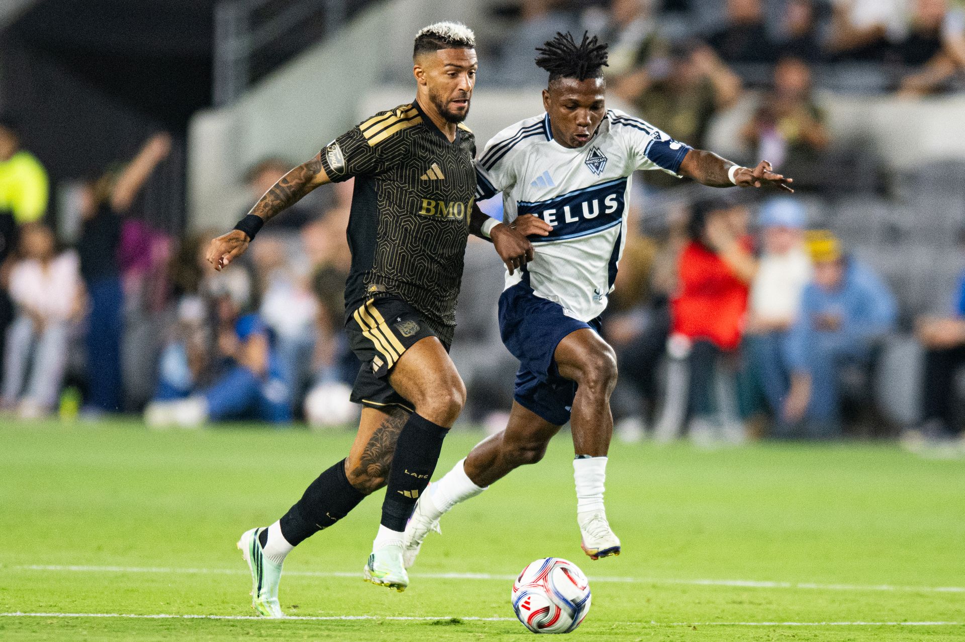 Denis Bouanga (99) fights for the ball against the Whitecaps