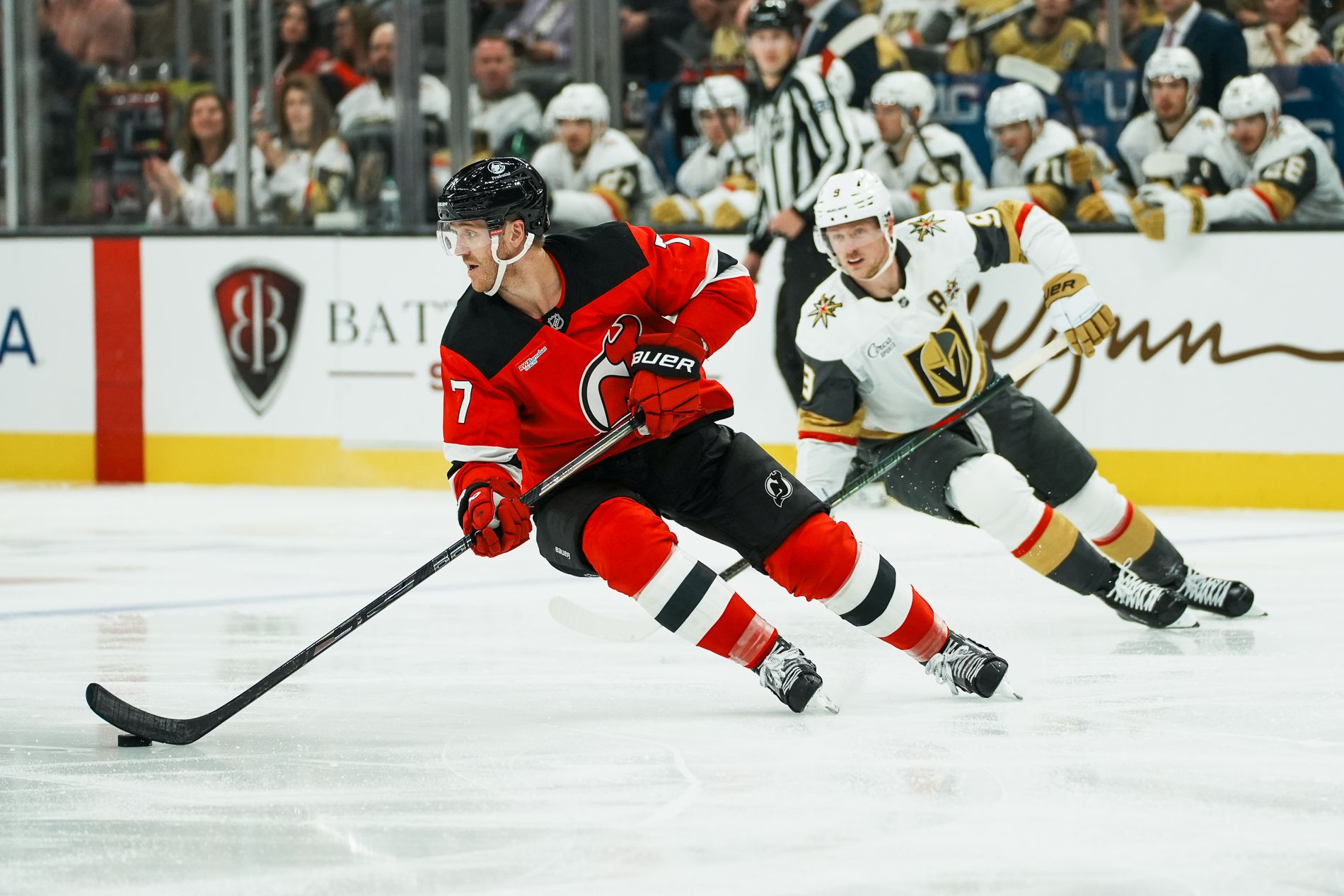 Dougie Hamilton carries the puck with Jack Eichel in pursuit